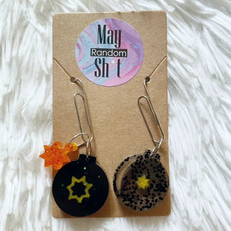 21027-cherry Pendientes únicos con forma de bomba de resina transparente y negra y estrellas de color amarillo y naranja con purpurina.